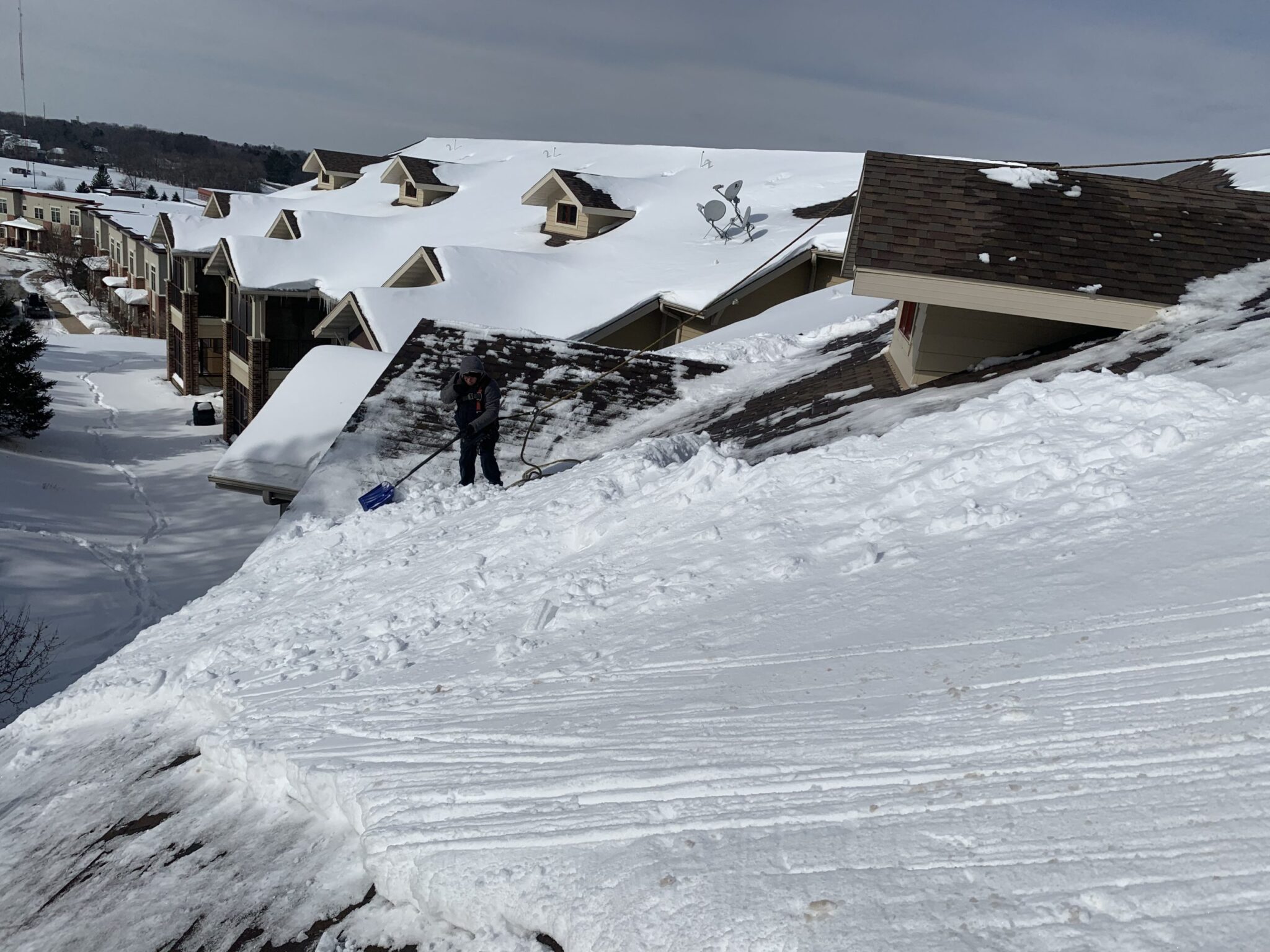 Worker shoveling snow from a home's roof